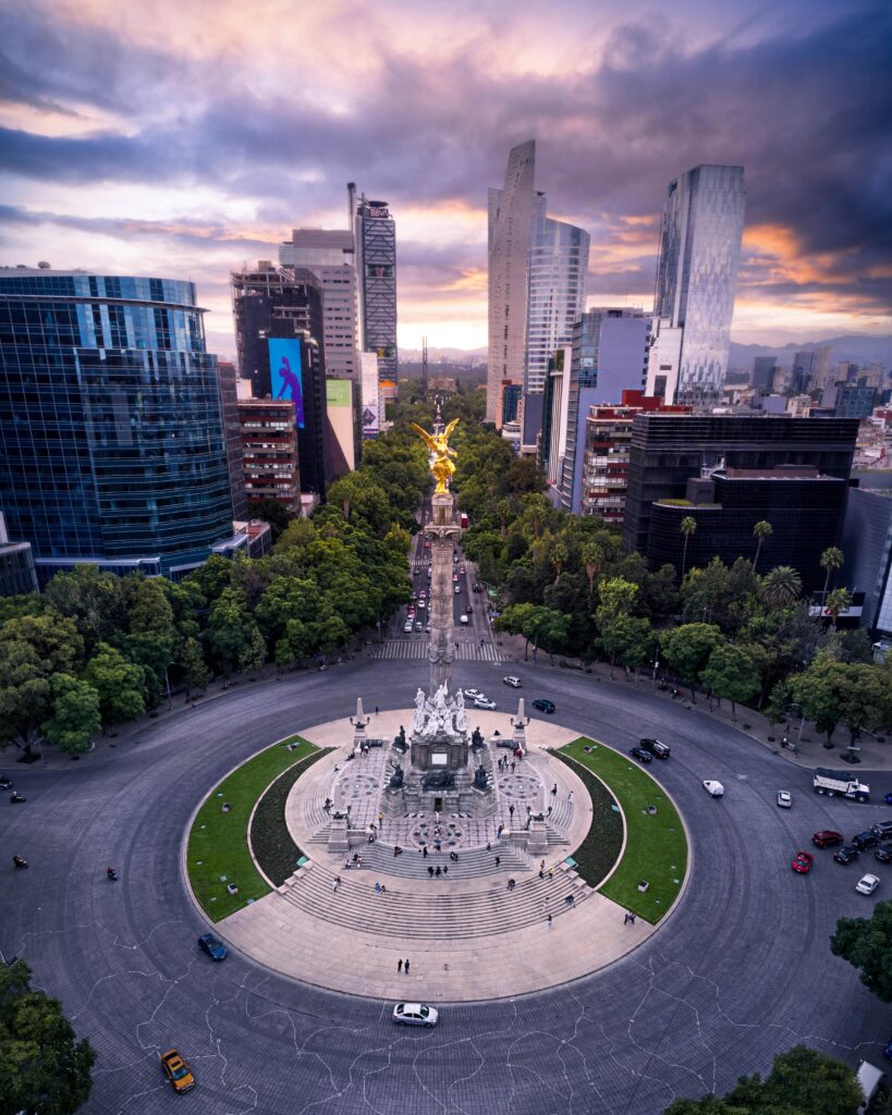 Stunning aerial view of Ángel de la Independencia in Mexico City with surrounding skyline at sunset.